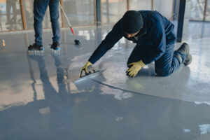 The worker applies gray epoxy resin to the new floor